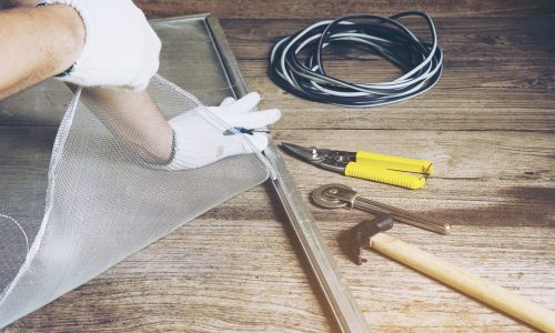 Man is working with mosquito wire screen installation